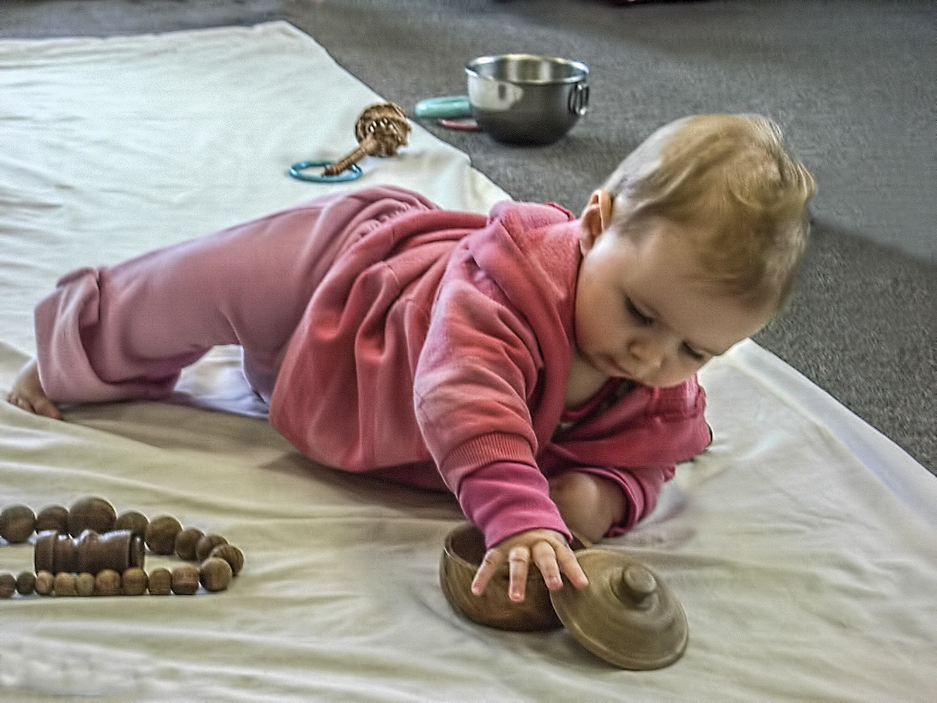 Baby exploring wooden objects while on their stomach while in a RIE® Parent Infant Guidance™ Class. 