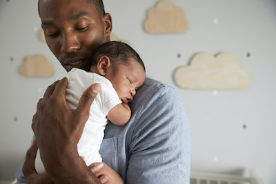 Father holding newborn baby in nursery.