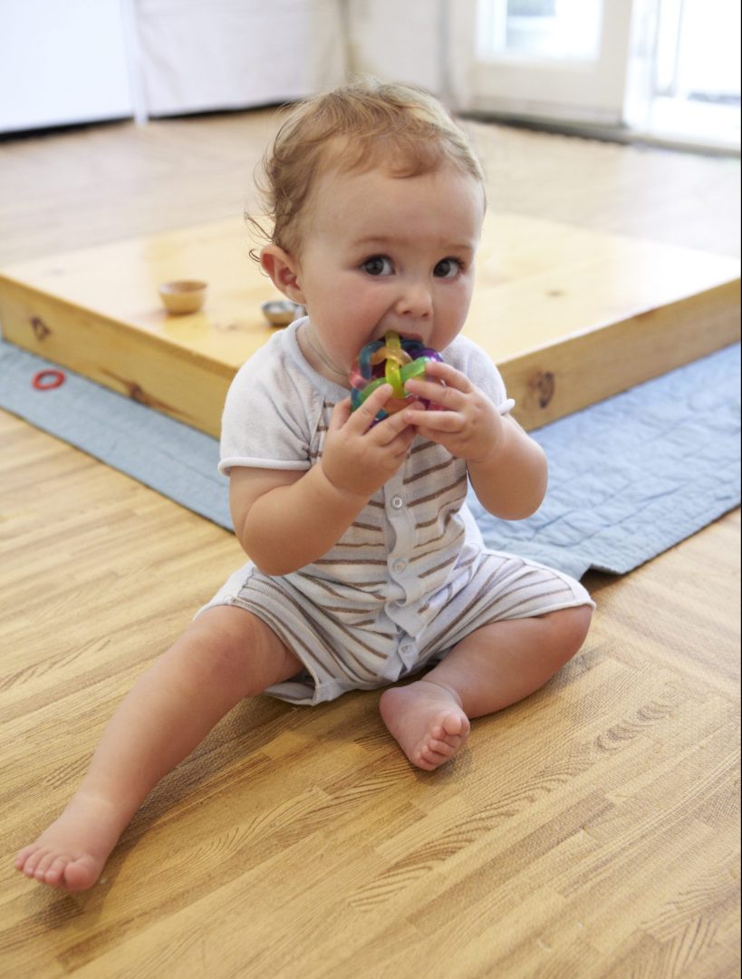 Infant at a RIE® Parent-Infant Guidance™ Class exploring an object near a low ramp.