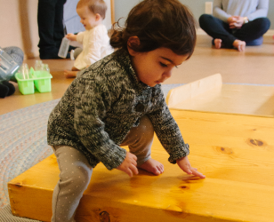 Toddler climbing down off a ramp during a RIE® Parent Infant Guidance™ Class