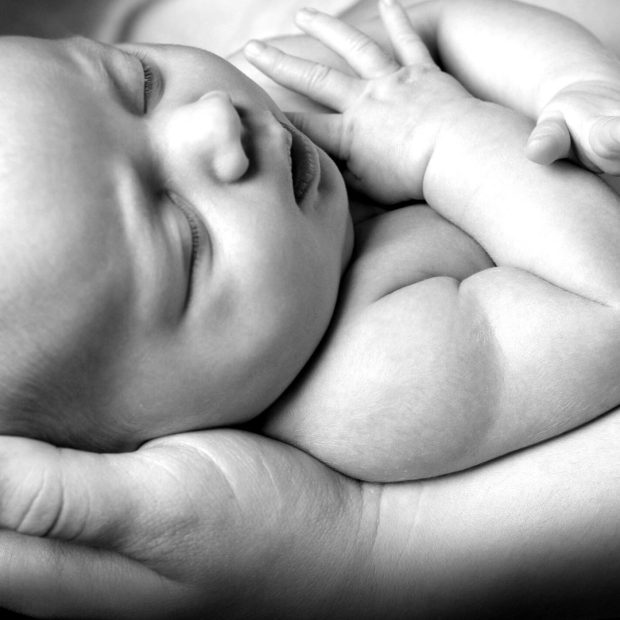 Newborn infant resting peacefully in mother's arms.